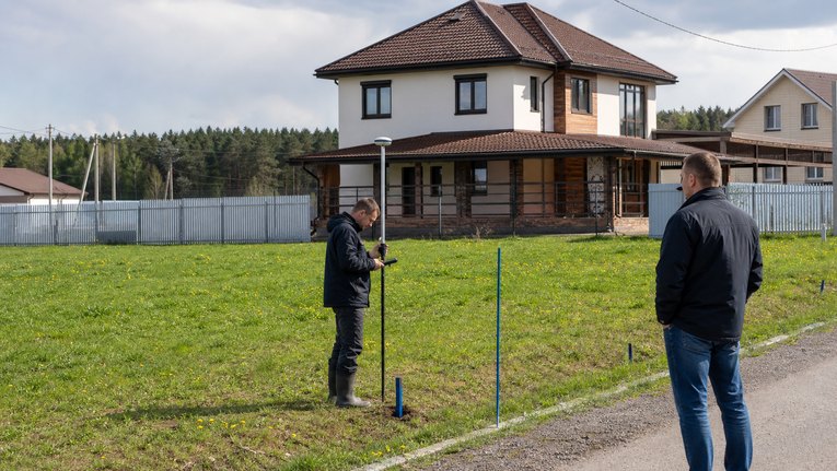 Кадастровый инженер измеряет участок и контур жилого дома
