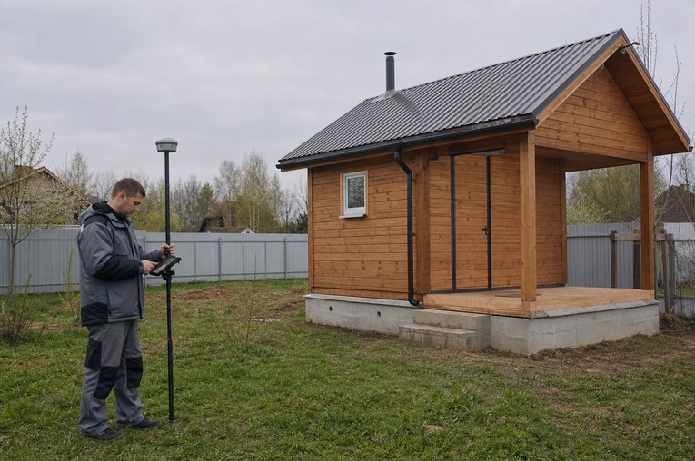 Кадастровый инженер измеряет хозяйственную постройку